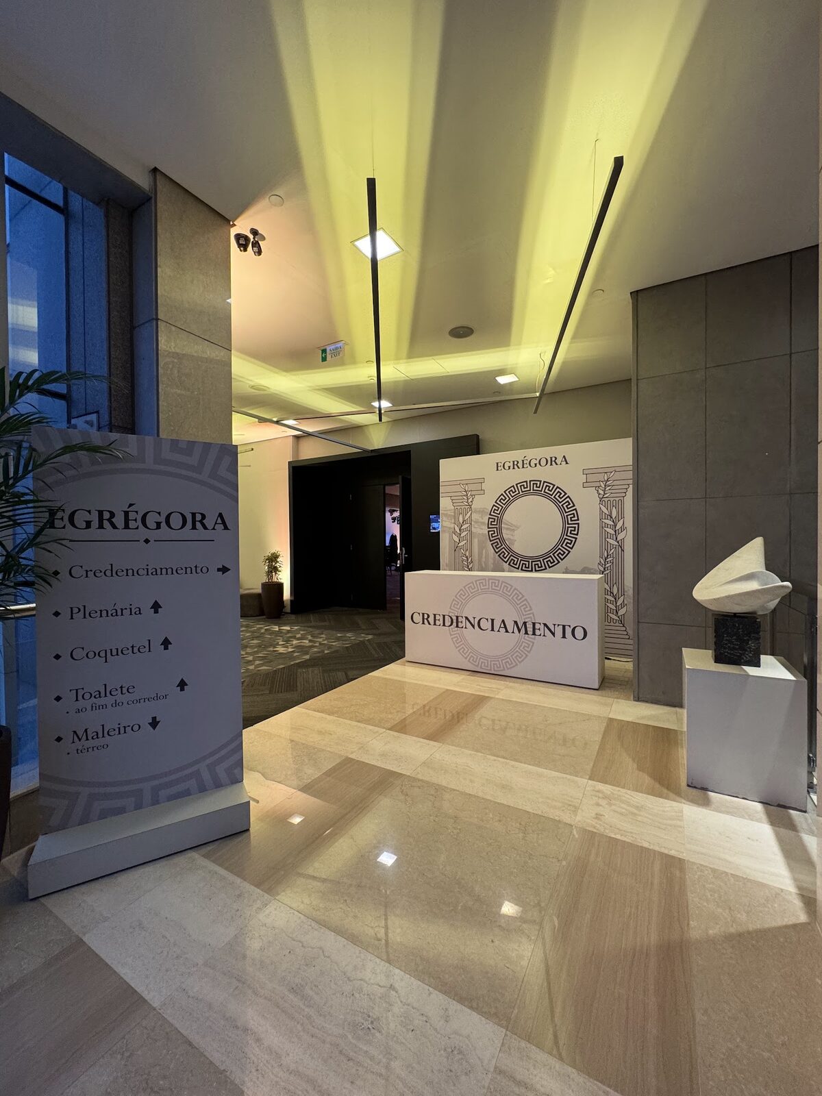 Credenciamento com balcão cenográfico, totens de sinalização e piso de mármore em evento corporativo