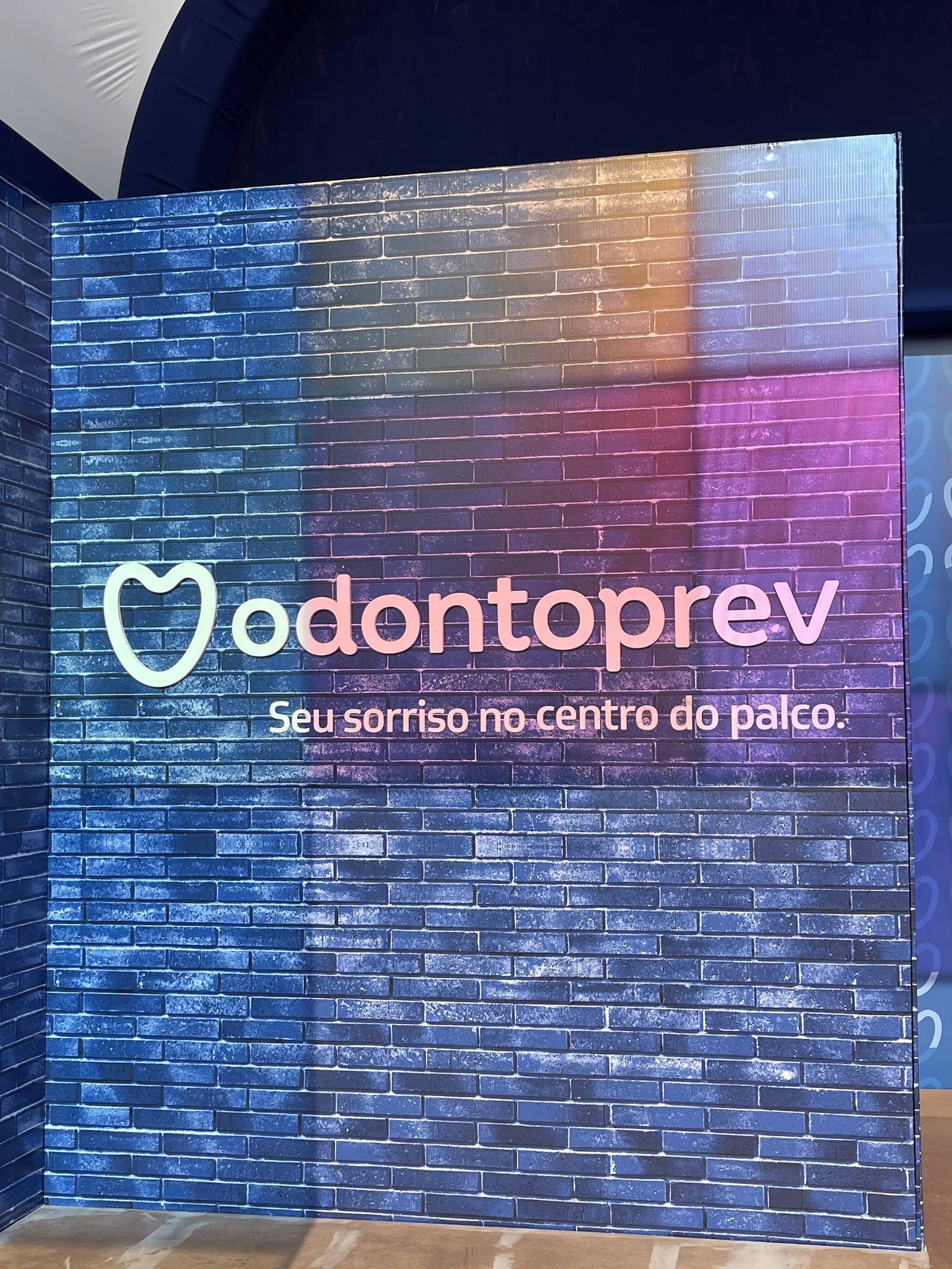 Painel cenográfico com efeito de luz colorida sobre textura de tijolos em evento