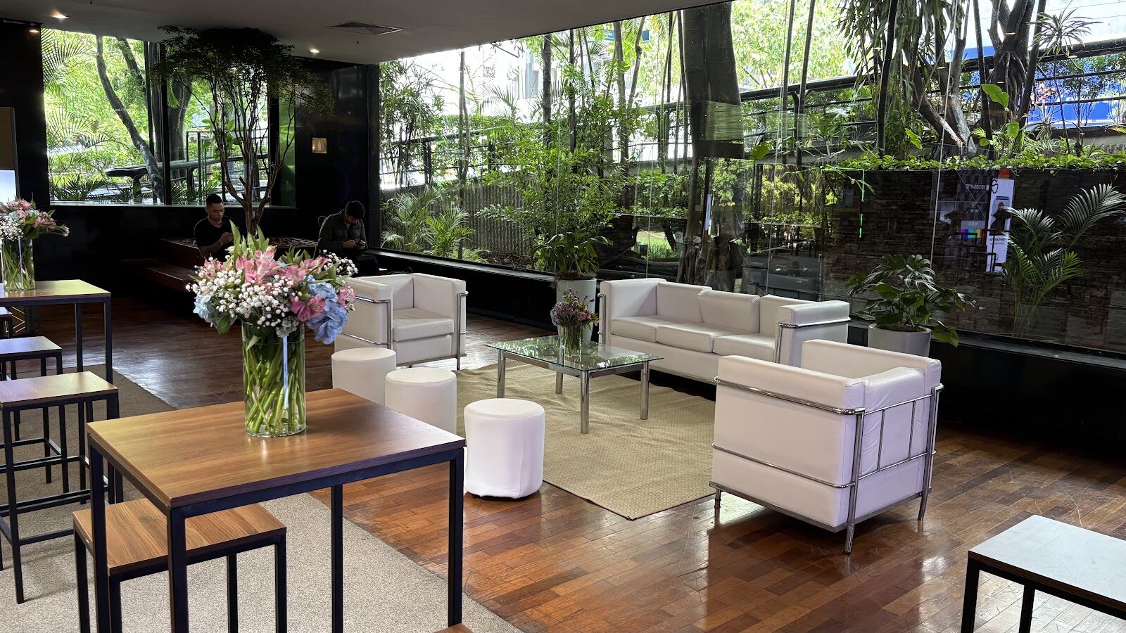 Lounge cenográfico com sofás brancos e arranjos florais em evento temático