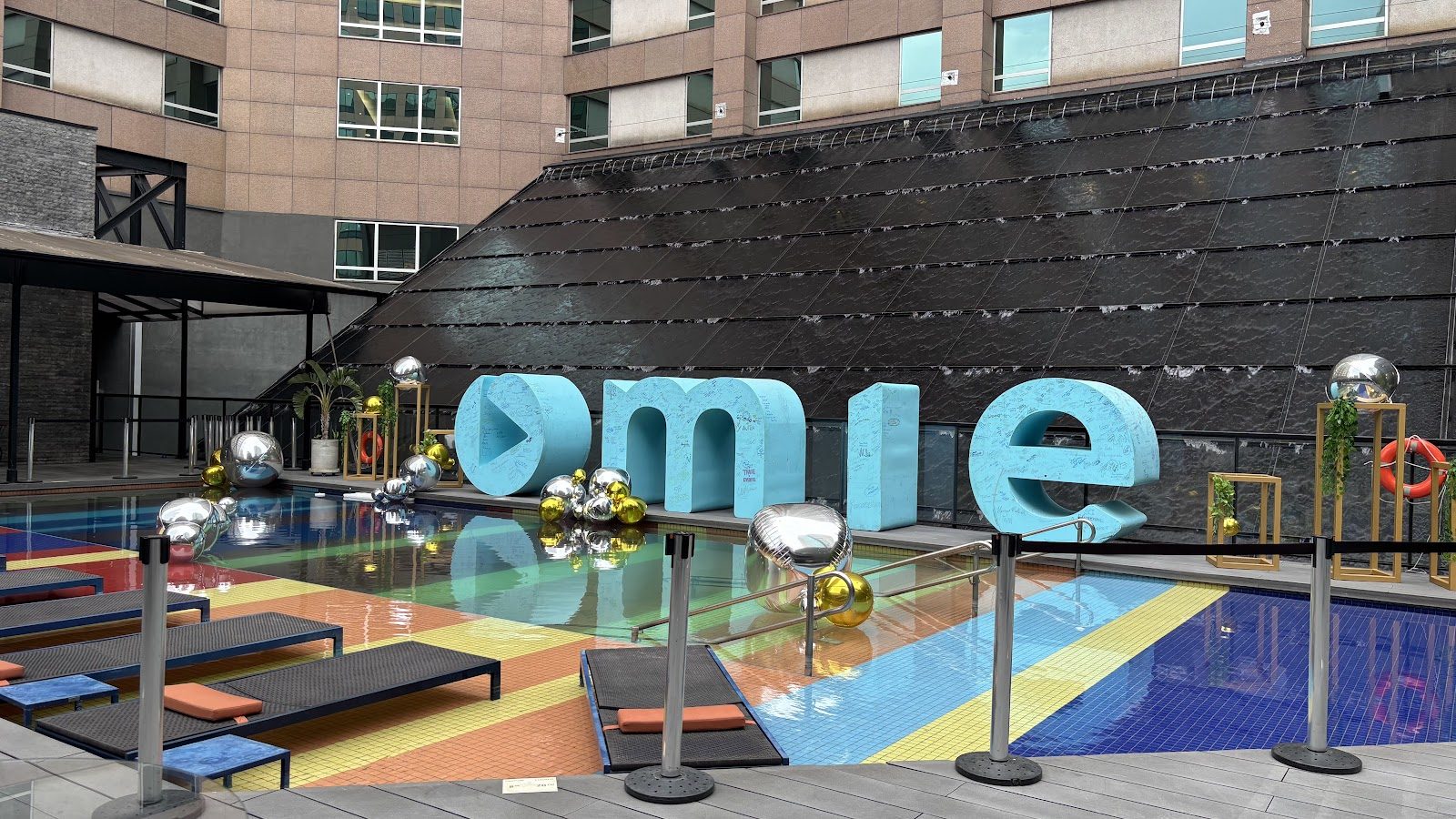 Letras gigantes decorativas à beira de piscina em evento corporativo ao ar livre