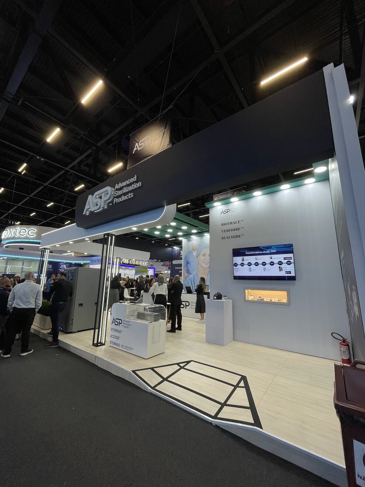 Entrada de stand com recepção aberta e sinalização clara em feira de negócios