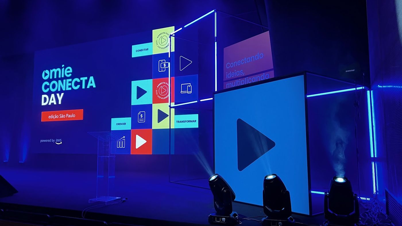 Palco cenográfico de town hall corporativo com telão LED, cubo de neon e iluminação cênica