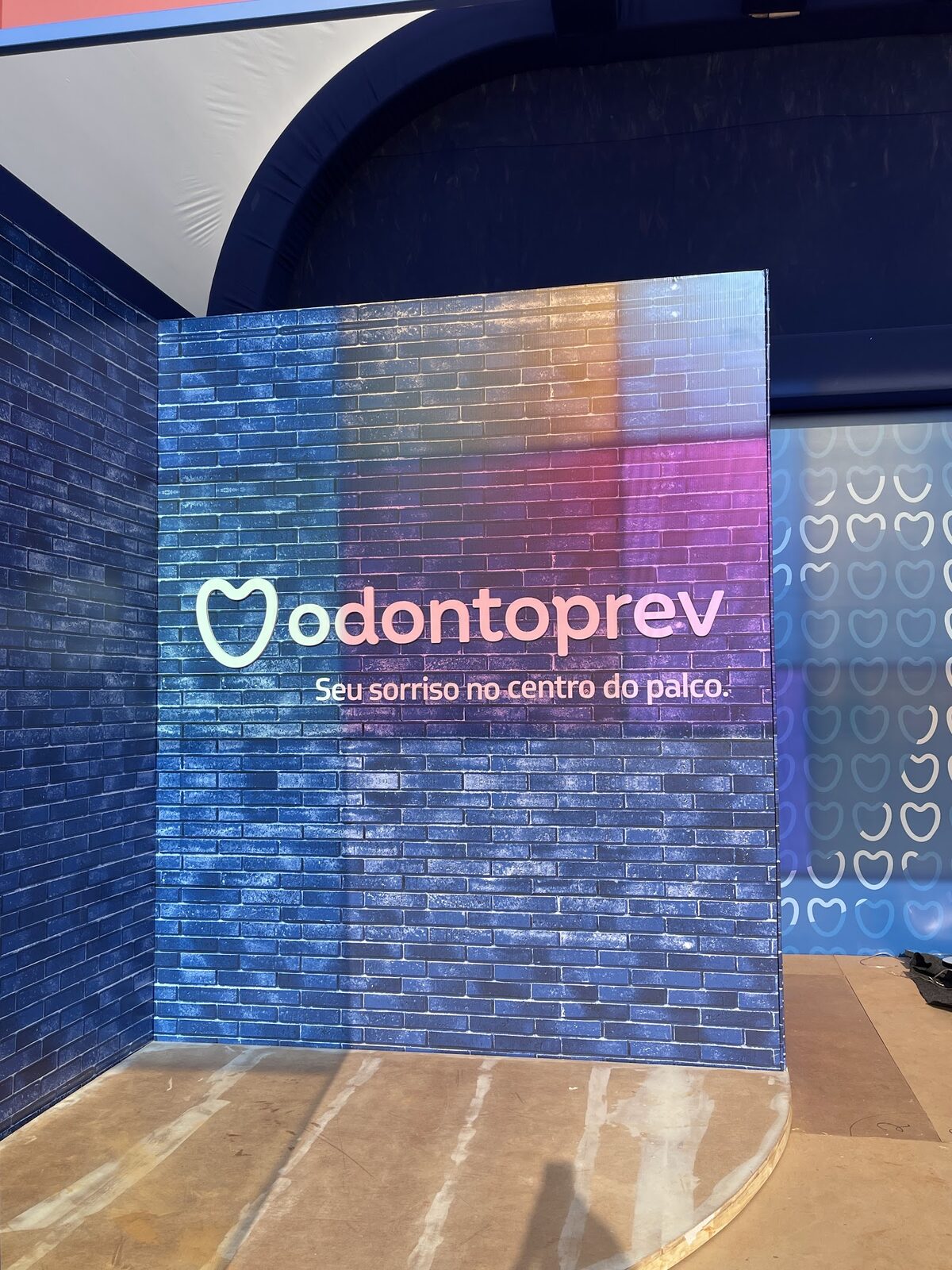 Painel cenográfico de tijolos coloridos com logo em fase de montagem no galpão
