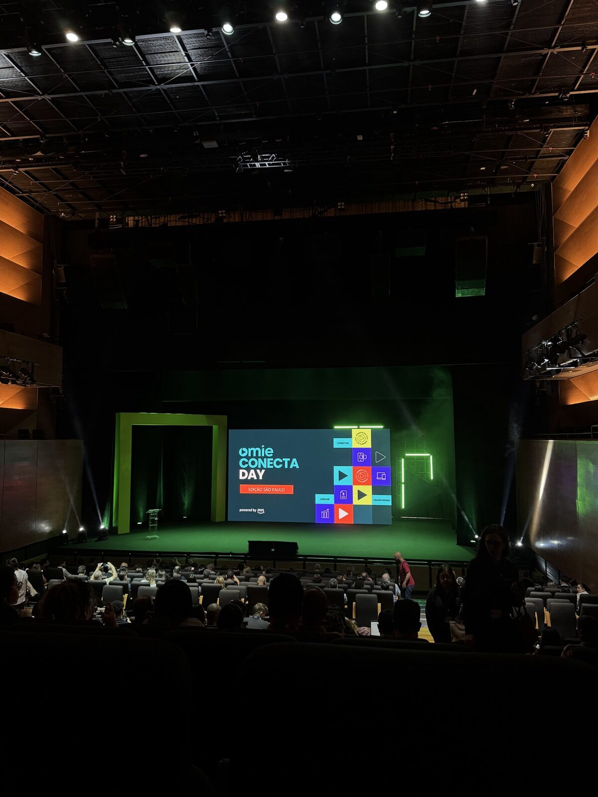 Palco de auditório com portal cenográfico amarelo e moldura verde em evento corporativo