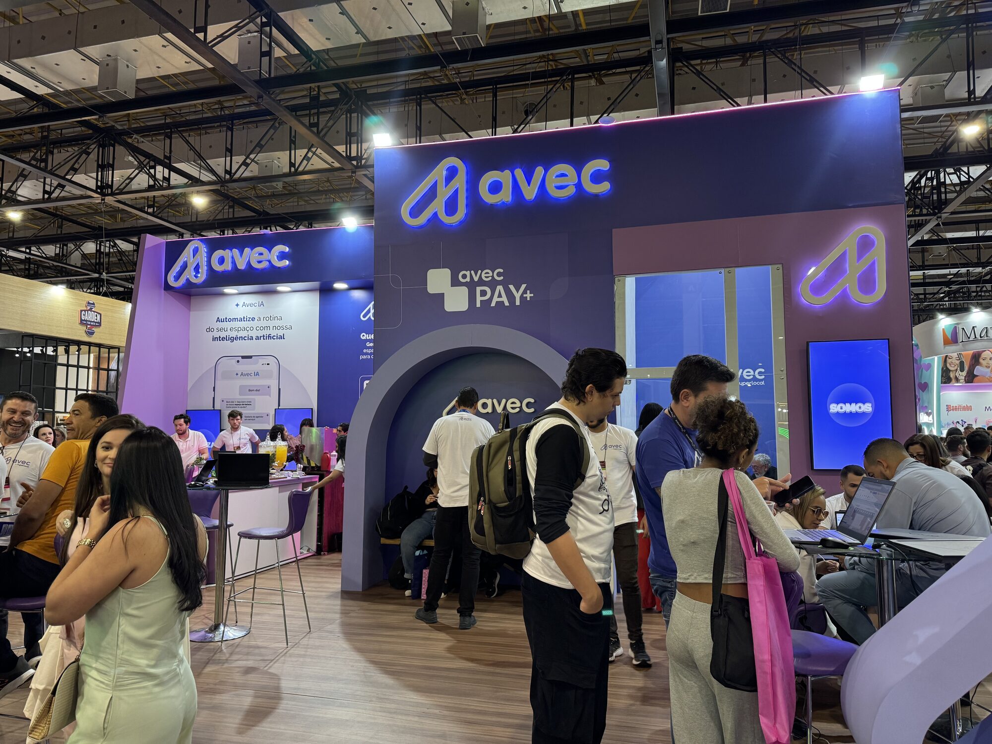 Stand de ponta de 80 m² da Avec na Beauty Fair 2025 com logo retroiluminado e LED roxo, montado pela Atom Cenografia