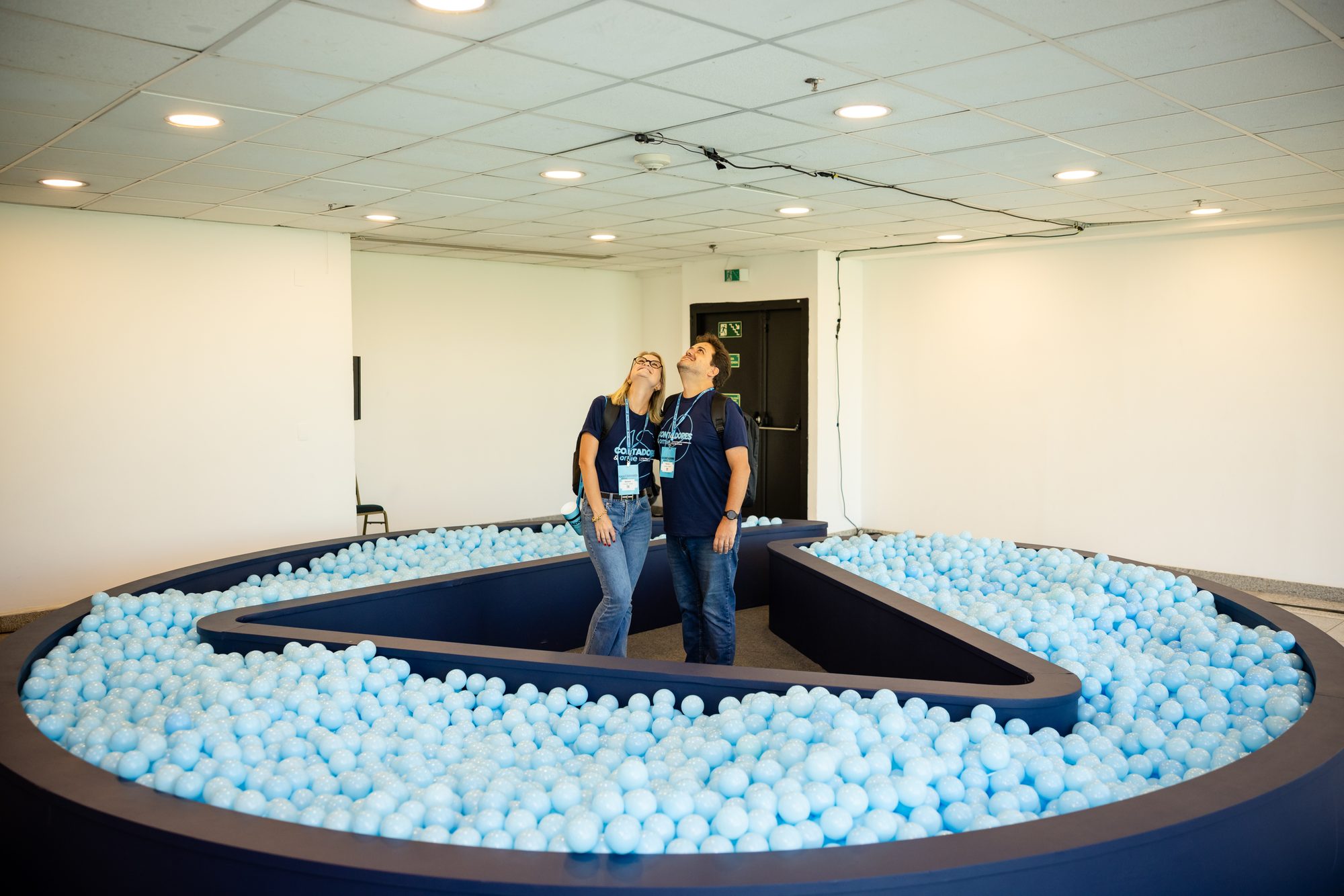 Piscina de bolinhas construída no formato do símbolo Omie, com participantes observando a estrutura — cenografia para convenção