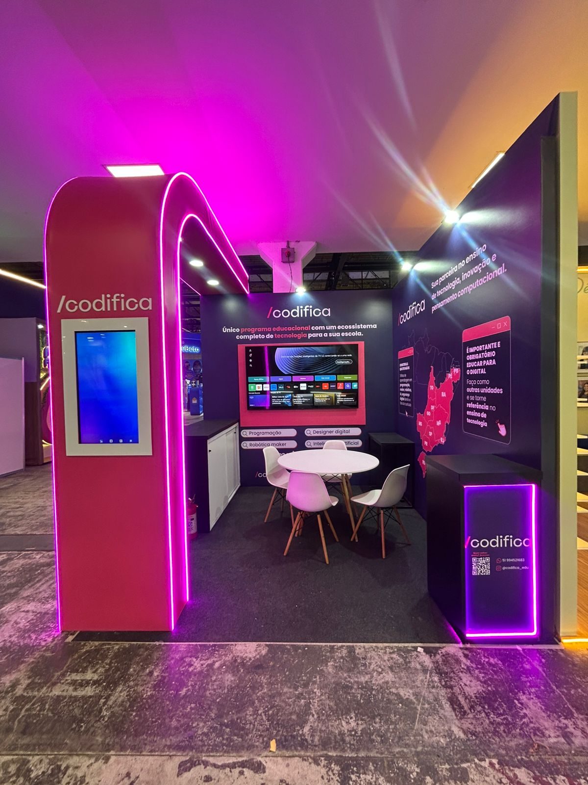 Estande de esquina da Codifica na Bett Brasil, com painel curvo iluminado em roxo e totem de entrada com tela