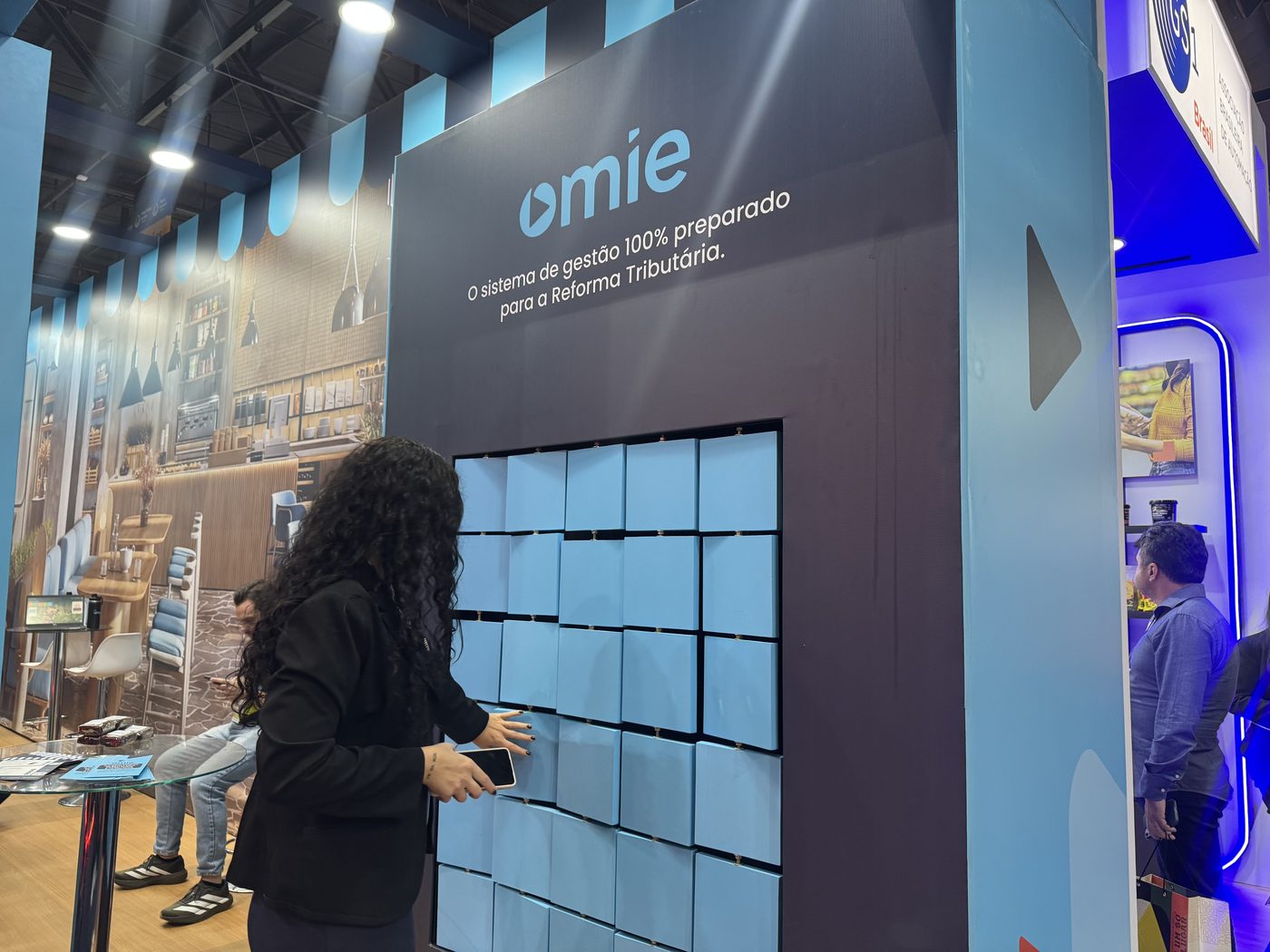 Painel iluminado em mosaico do estande da Omie na Fispal Food Service, com peças azuis de 20 por 20 centímetros